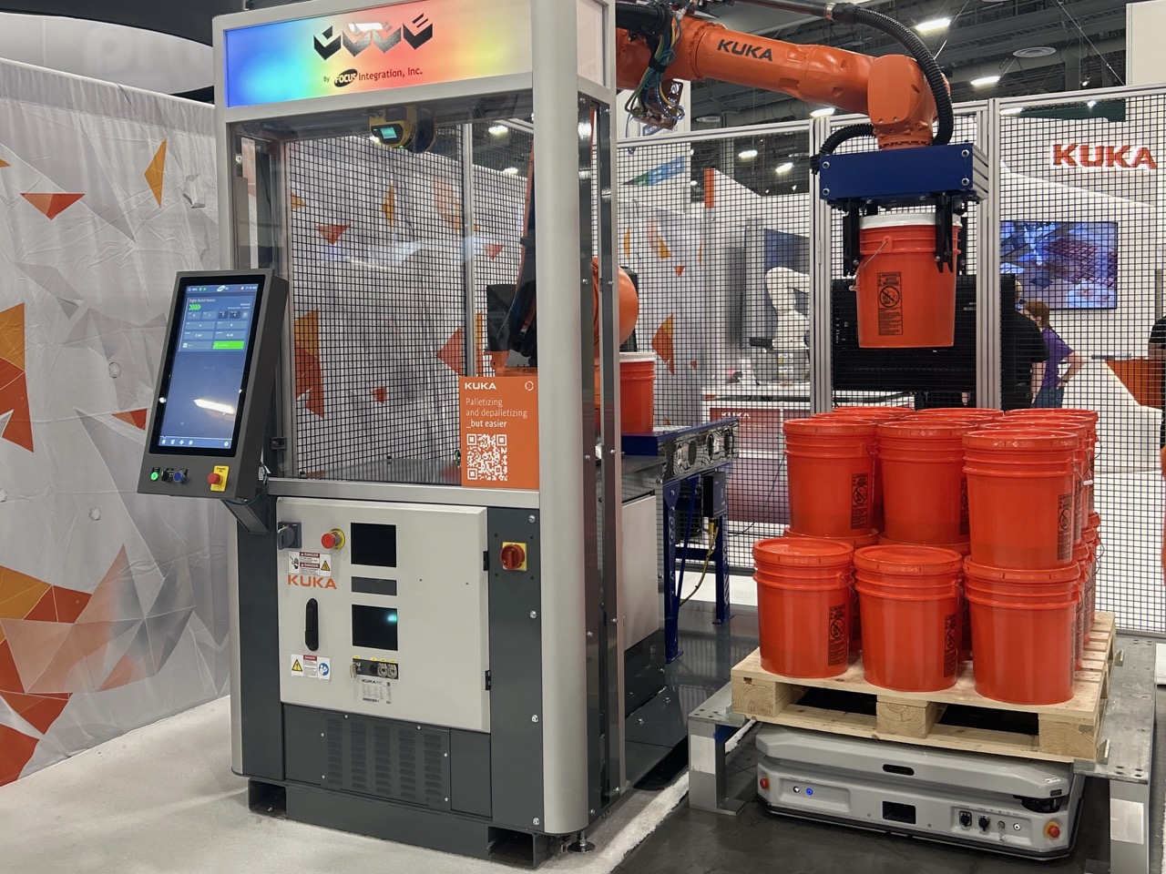 KUKA industrial robotics exhibition booth with automated arm system and red industrial containers on display