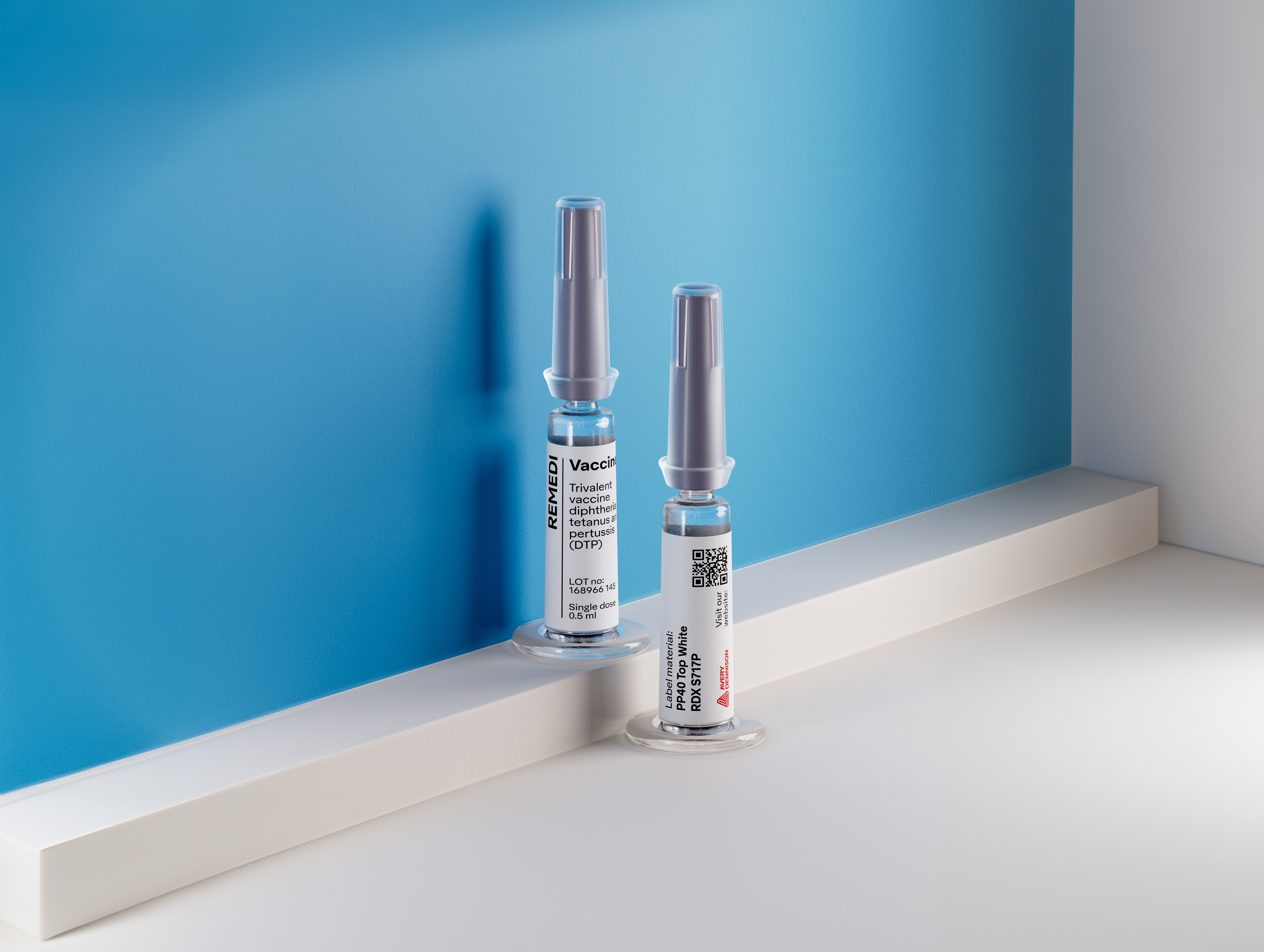 Two vaccine vials with metallic caps displayed on white surface against blue background