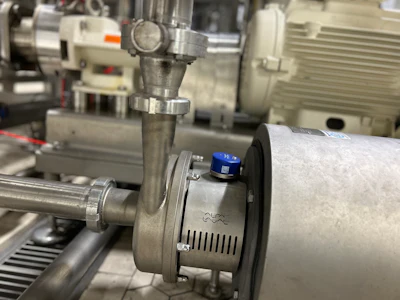 Industrial pump assembly with blue valve in manufacturing facility with motors and equipment