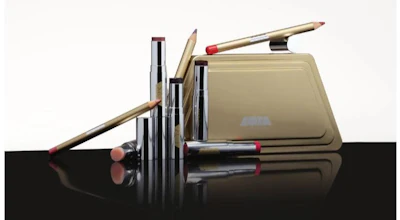 Cosmetic makeup collection featuring brushes, lipsticks, and eyeshadow palette in neutral and mauve tones