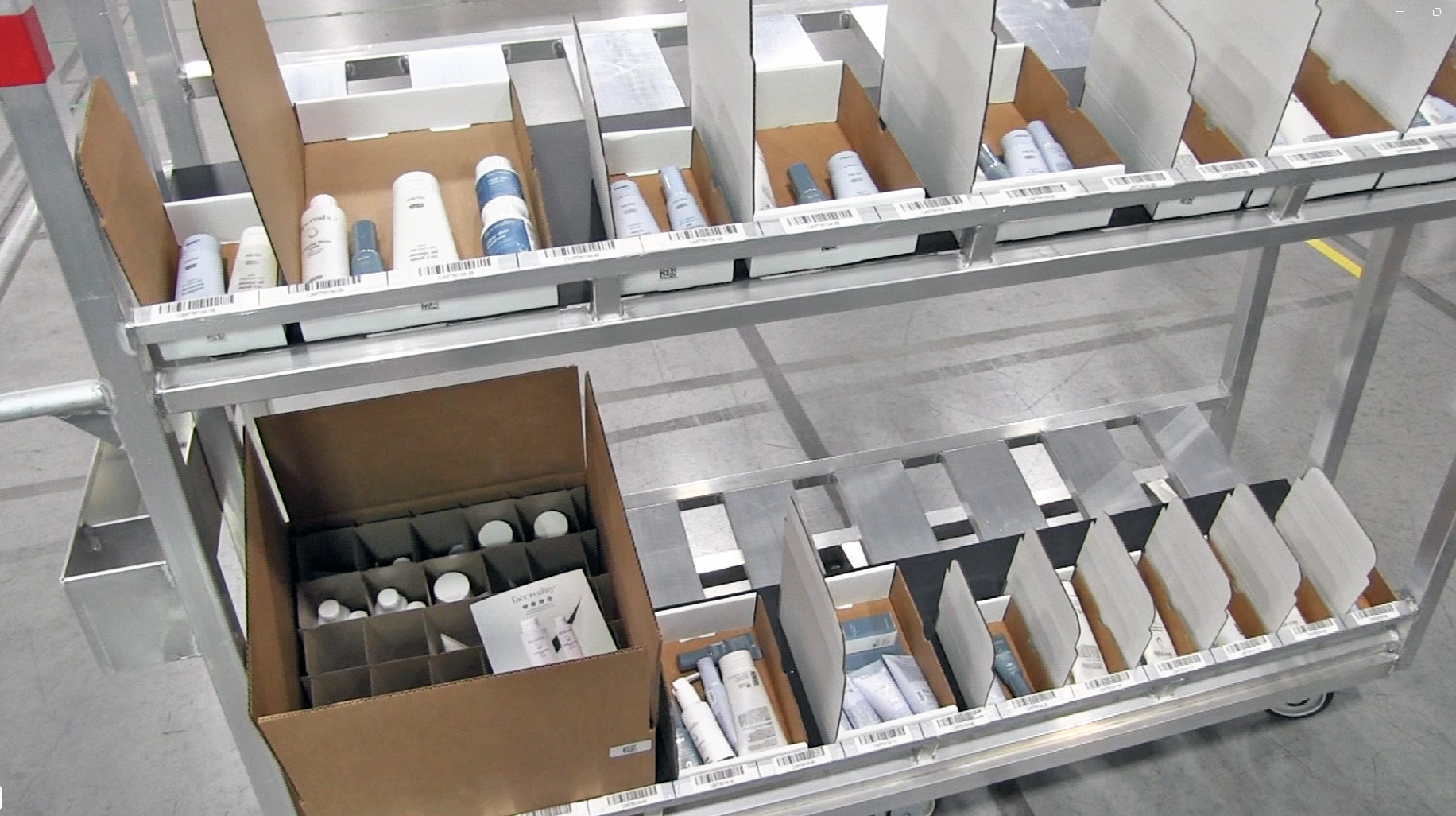 Cases and cartons are selected by the dimensioning system and staged with barcode-labeled positions before picking begins, removing the packer’s discretion over box size.