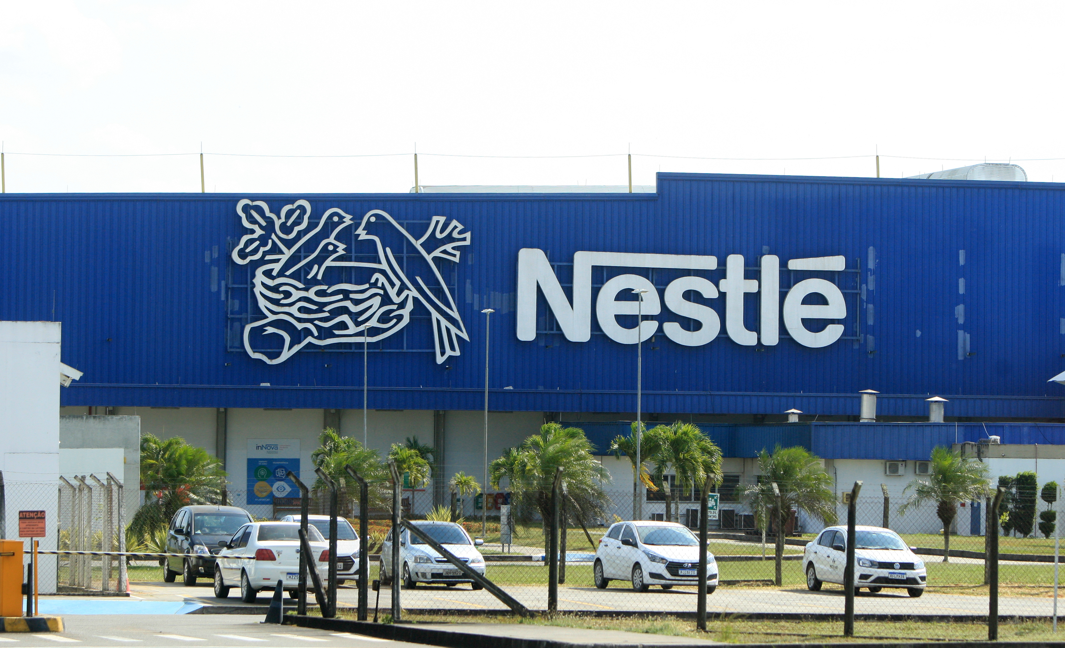 Nestlé manufacturing facility with blue facade, company logo, and parked vehicles in front