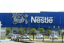 Nestlé manufacturing facility with blue facade, company logo, and parked vehicles in front