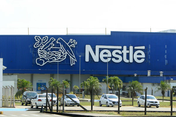 Nestlé manufacturing facility with blue facade, company logo, and parked vehicles in front