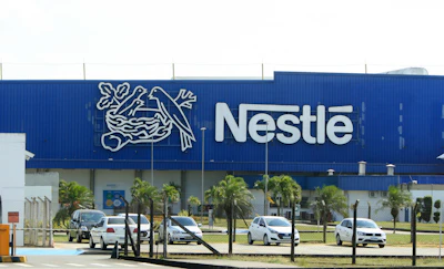 Nestlé manufacturing facility with blue facade, company logo, and parked vehicles in front