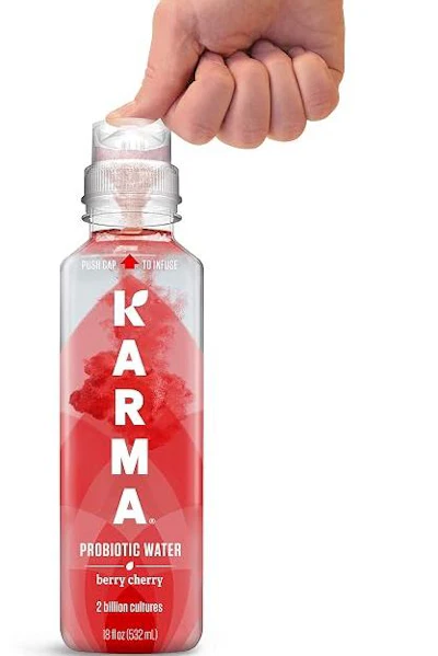 Hand holding KARMA probiotic water bottle in berry cherry flavor with 2 billion cultures