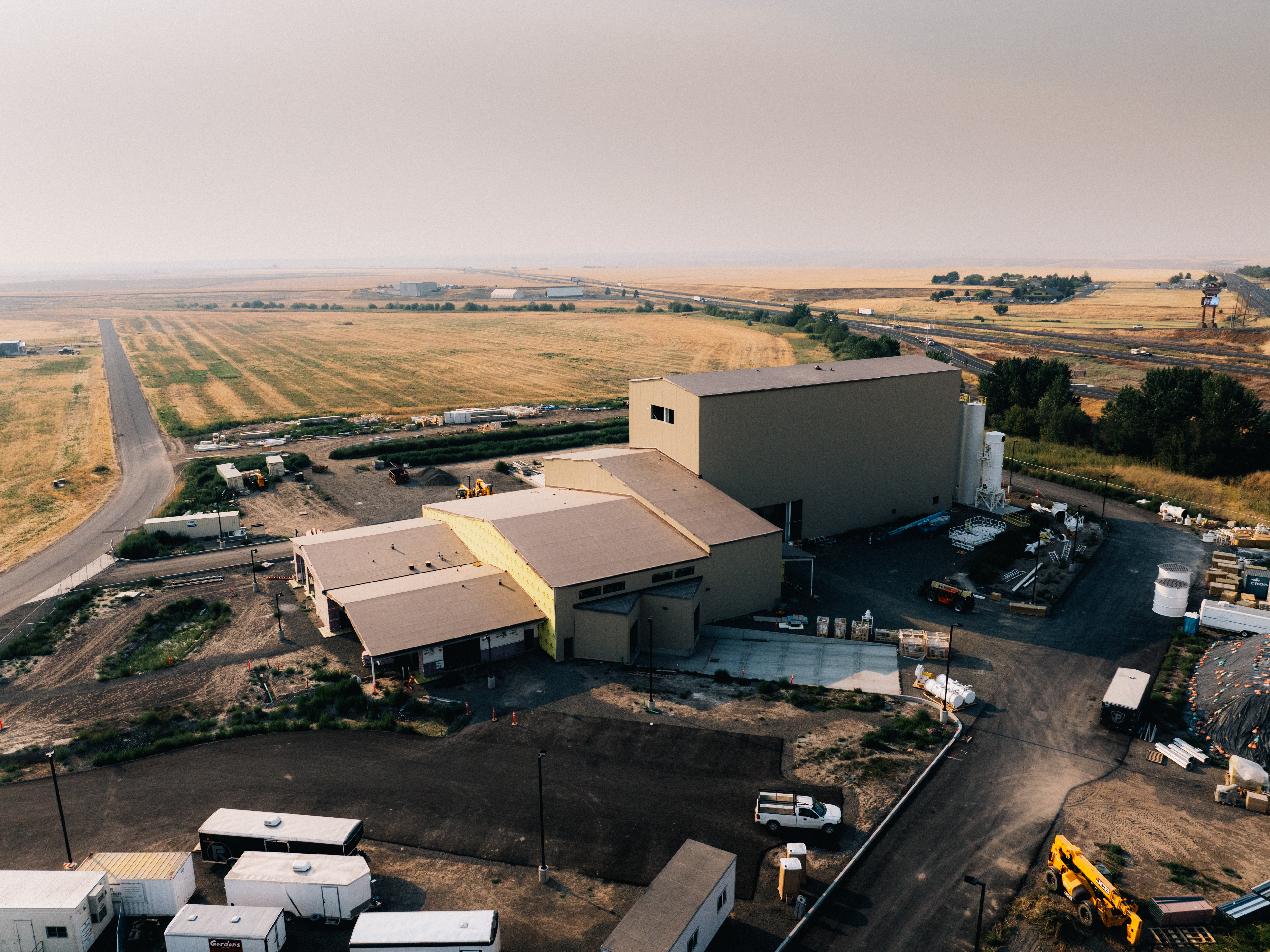 Aerial view of industrial facility with large storage building and agricultural fields in rural landscape