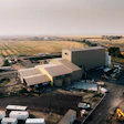 Aerial view of industrial facility with large storage building and agricultural fields in rural landscape