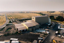 Aerial view of industrial facility with large storage building and agricultural fields in rural landscape