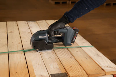 Worker using cordless power tool on wooden deck planks with green chalk line