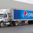 White Pepsi delivery truck with blue branded trailer parked against building
