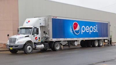 White Pepsi delivery truck with blue branded trailer parked against building
