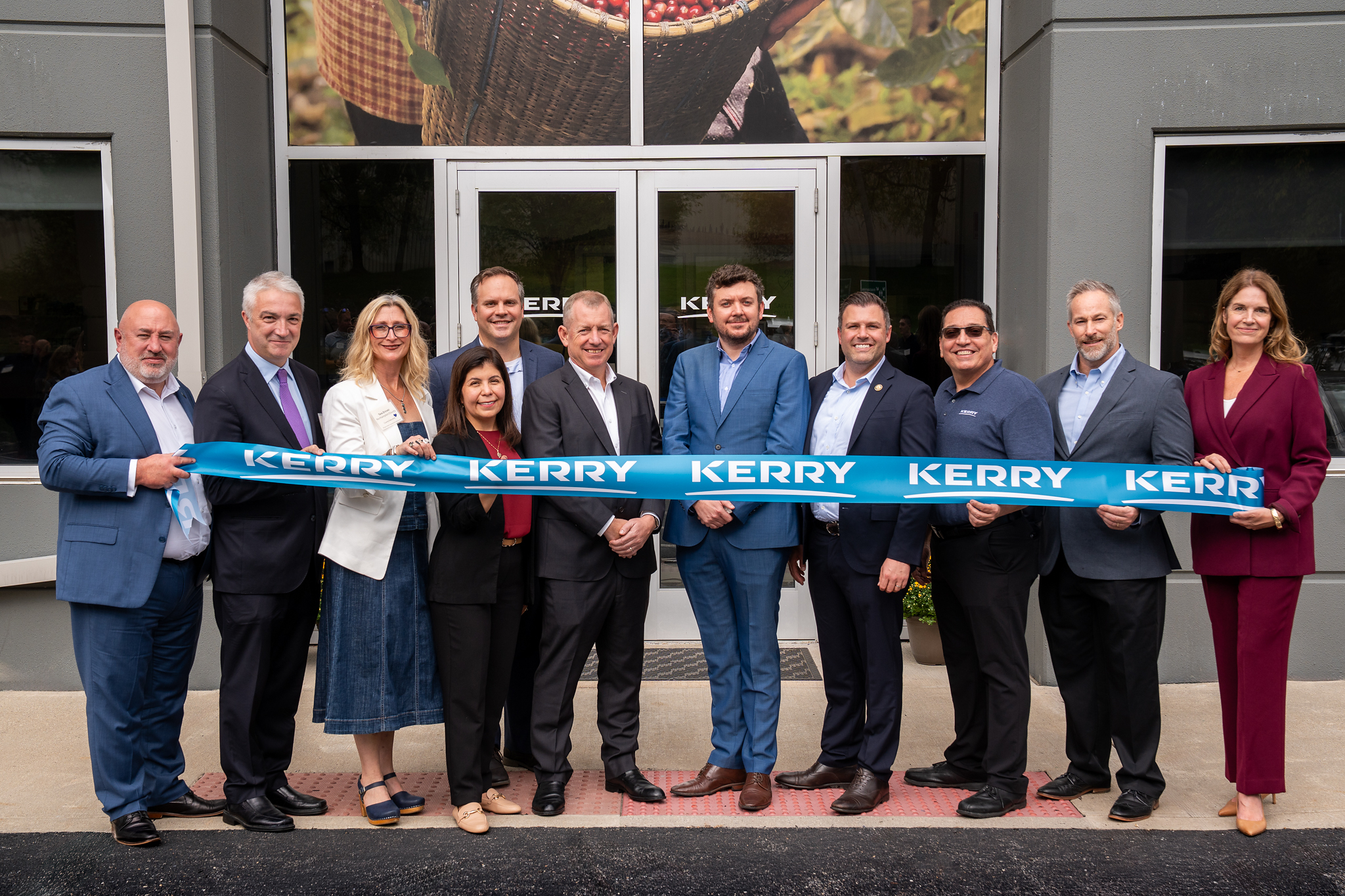 Group of business professionals holding blue Kerry branded ribbon at facility opening ceremony