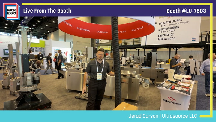 Professional at Pack Expo booth #LU-7503 demonstrating packaging equipment under red umbrella display