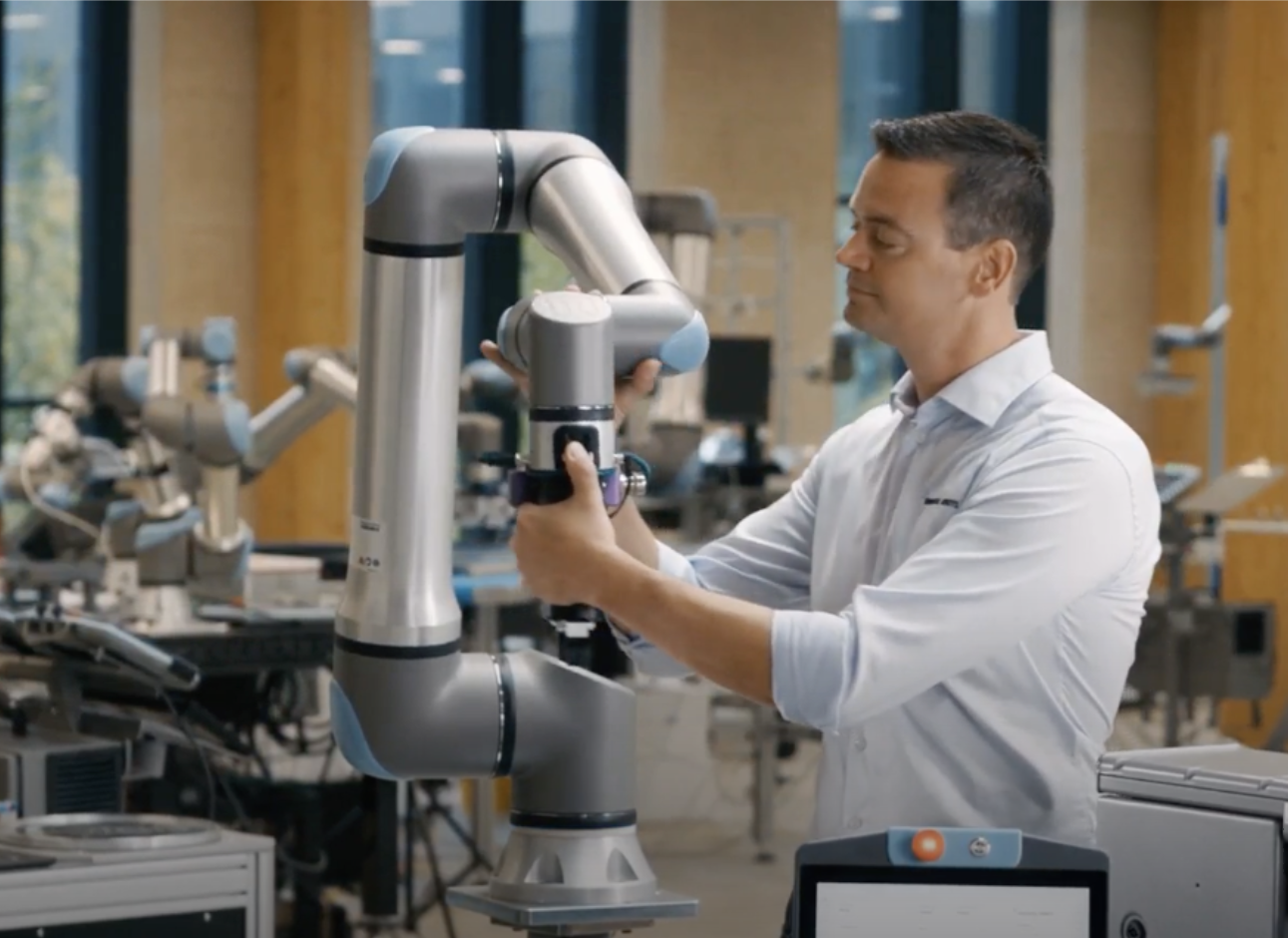 Engineer operating a white collaborative robotic arm in an industrial laboratory setting