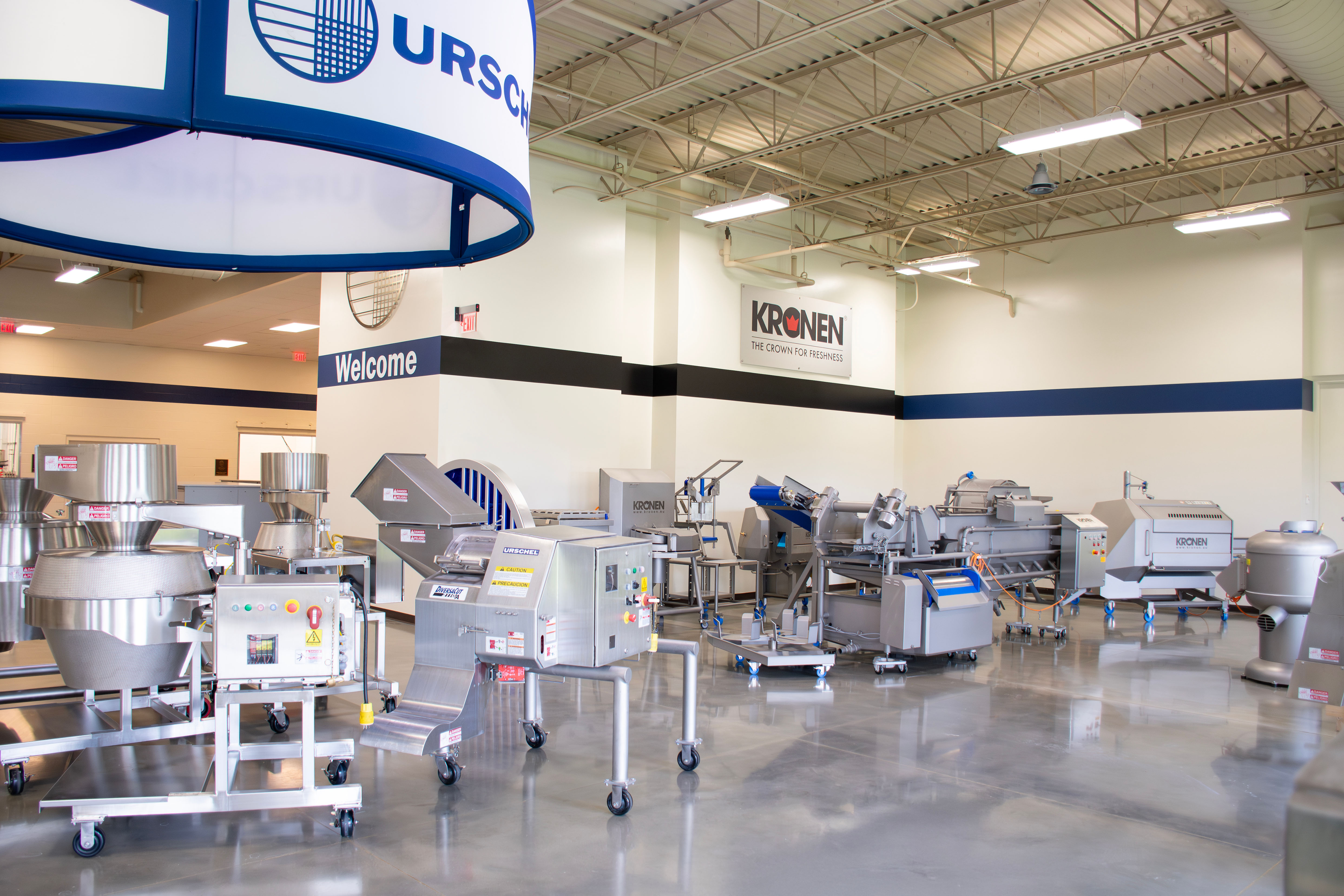 Industrial facility showroom displaying food processing equipment with blue and white branded signage