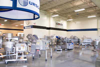 Industrial facility showroom displaying food processing equipment with blue and white branded signage