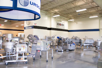 Industrial facility showroom displaying food processing equipment with blue and white branded signage